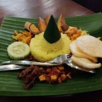 Foto nasi tumpeng khas Galur yang lezat, disajikan dengan lauk pauk lengkap dan garnish tradisional, siap untuk dinikmati dalam acara spesial.