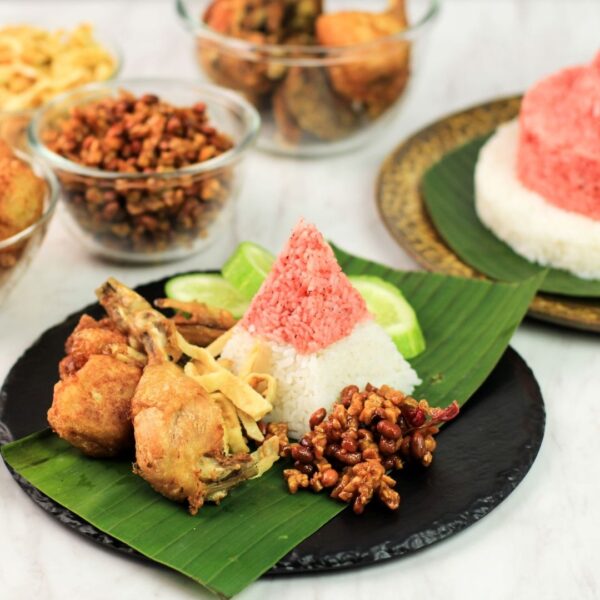 Foto nasi tumpeng khas Kemiri yang lezat, disajikan dengan lauk pauk lengkap dan garnish tradisional, siap untuk dinikmati dalam acara spesial.