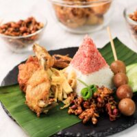 Foto nasi tumpeng khas Bener yang lezat, disajikan dengan lauk pauk lengkap dan garnish tradisional, siap untuk dinikmati dalam acara spesial.