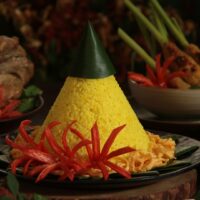 Foto nasi tumpeng khas Purbalingga yang lezat, disajikan dengan lauk pauk lengkap dan garnish tradisional, siap untuk dinikmati dalam acara spesial.