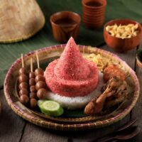 Foto nasi tumpeng khas Minggir yang lezat, disajikan dengan lauk pauk lengkap dan garnish tradisional, siap untuk dinikmati dalam acara spesial.