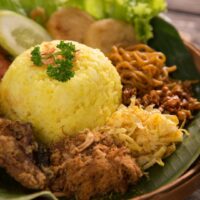 Foto nasi tumpeng khas Salam yang lezat, disajikan dengan lauk pauk lengkap dan garnish tradisional, siap untuk dinikmati dalam acara spesial.