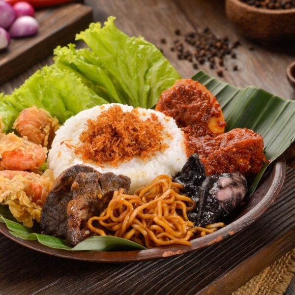 Foto nasi tumpeng khas Purbalingga yang lezat, disajikan dengan lauk pauk lengkap dan garnish tradisional, siap untuk dinikmati dalam acara spesial.